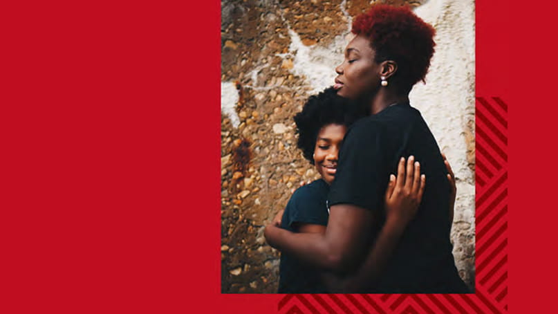 A Black woman and child hugging on a red background A Black woman and child hugging on a red background